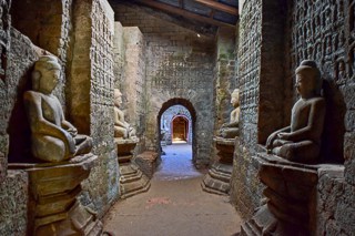 Buddhist statues along both sides of a corridor inside a temple in Mrauk U