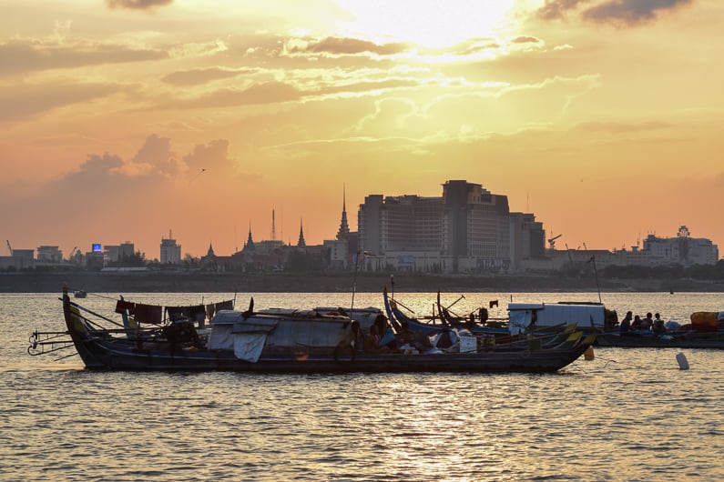 a fishing boat on the Mekong River at sunset with Phnom Penh in the background