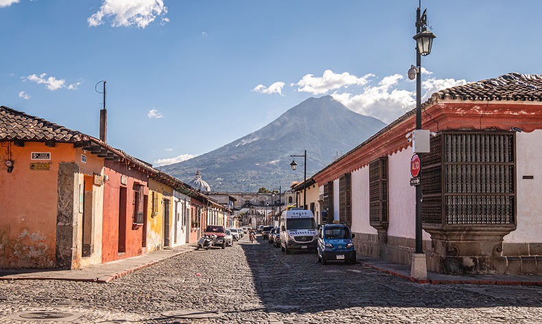 a street lined with colorful Spanish colonial buildings leading to a volcano