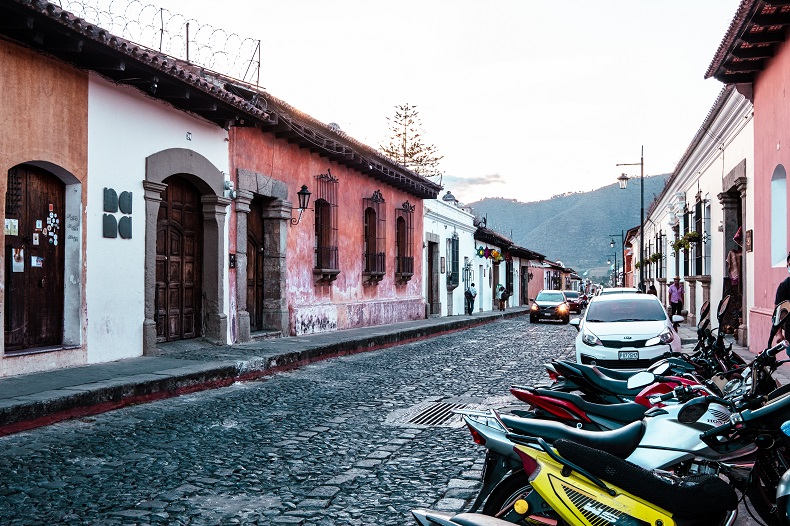 a street lined with colorful Spanish colonial buildings and motorcycles