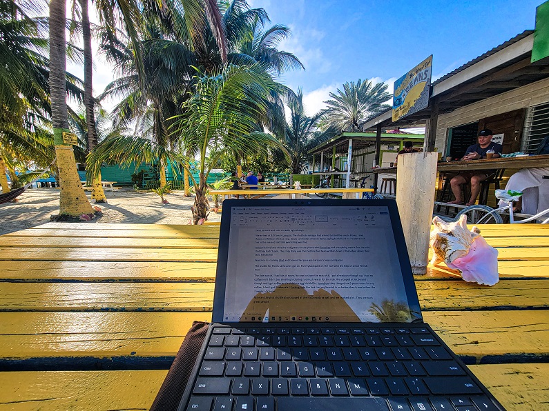 a laptop sitting on a yellow picnic table at the beach