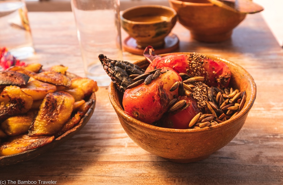 a bowl of fried plantains and another bowl of tomatoes, dried chiles, and pumpkin seeds