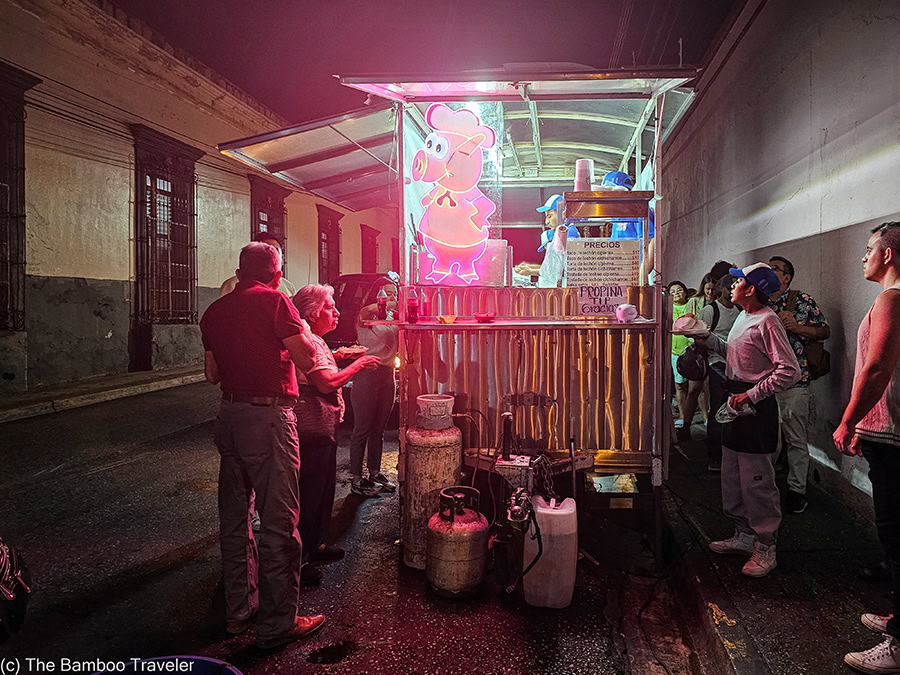 A group of people standing in front of a food cart at night