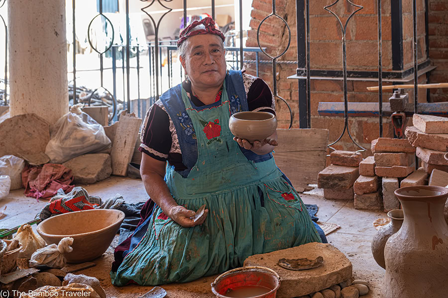 a woman sitting on the floor and holding out a piece of pottery on En Via tour Oaxaca