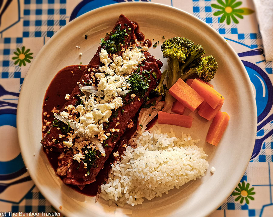 a plate of mole enchiladas, rice, and carrots
