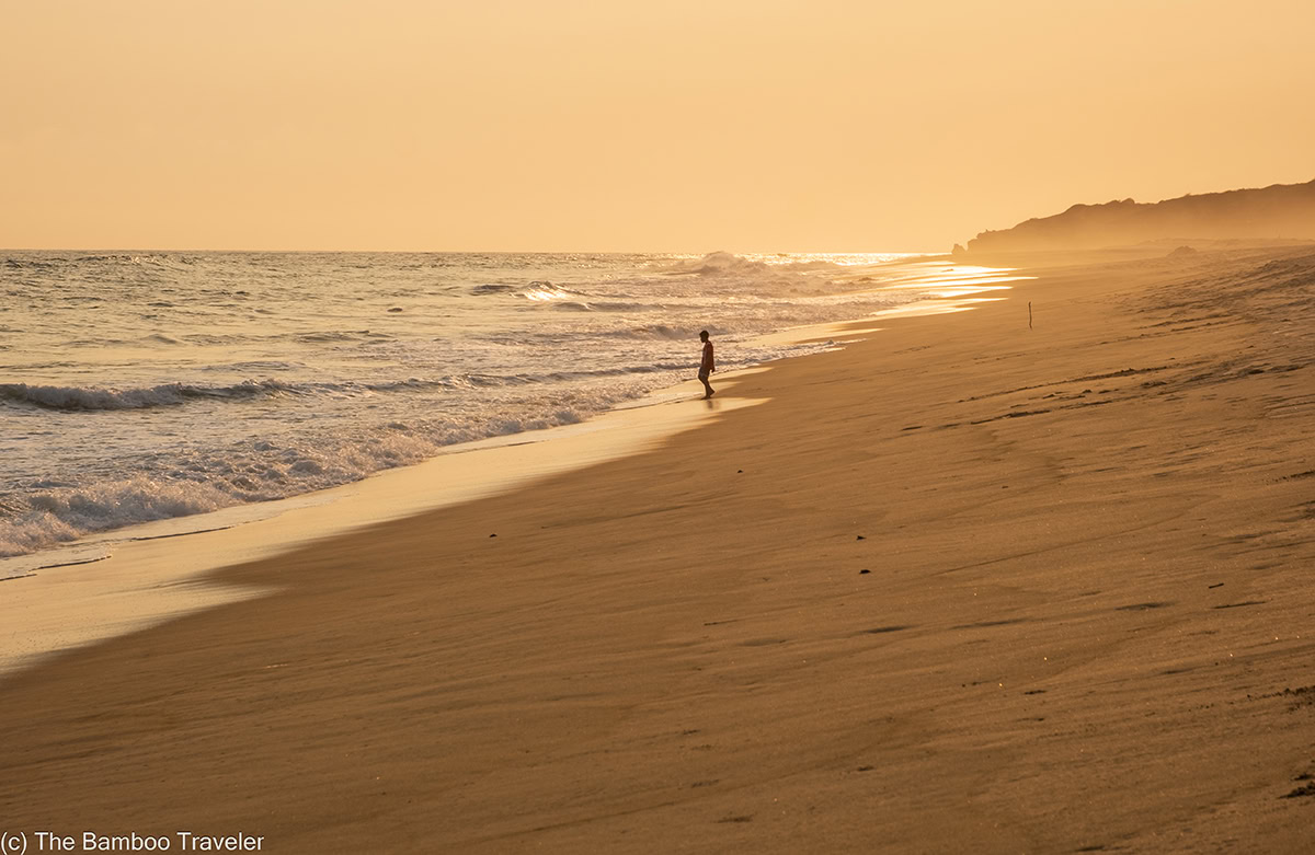 a boy walking on a beach in Puerto Escondido at sunset
