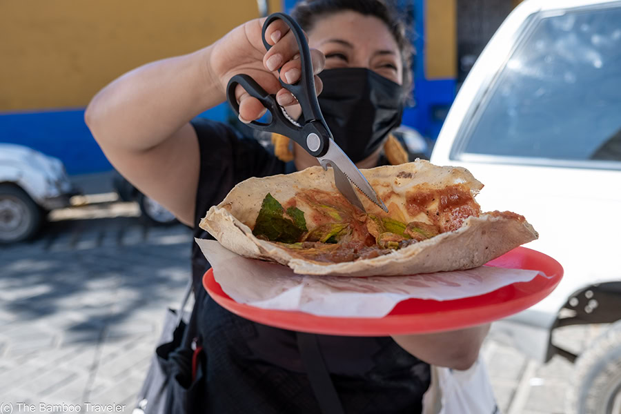 a woman cutting an empanada with a scissor