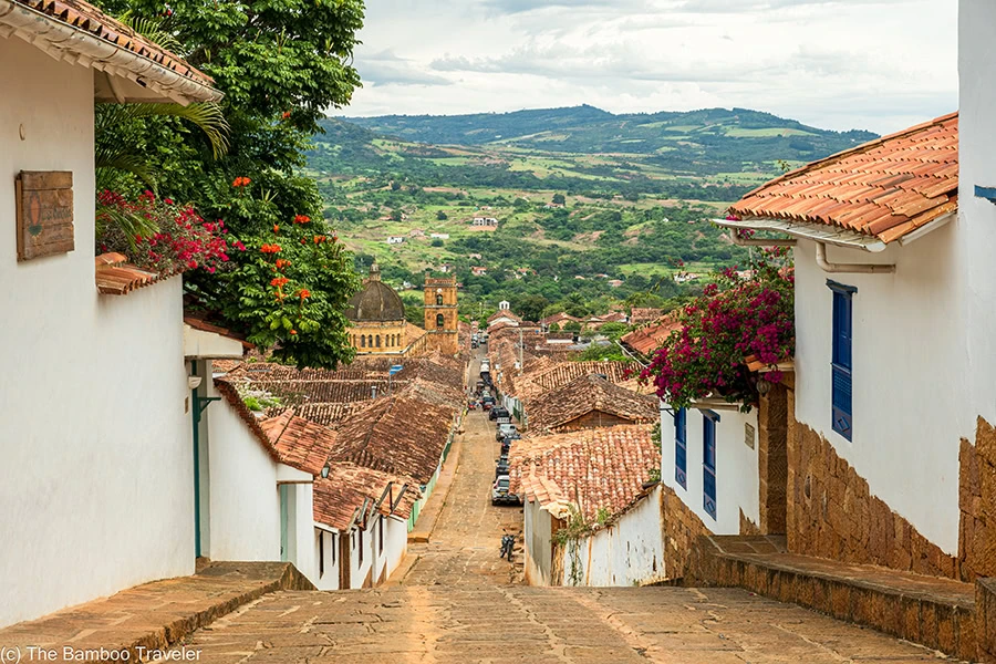 a street going downhill and lined with whitewashed one-story buildings.