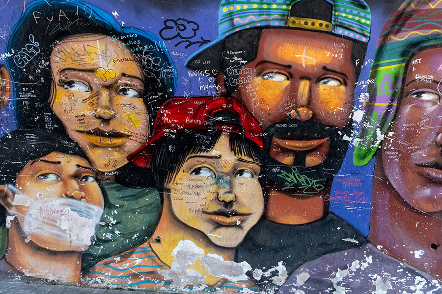 A mural with the faces of people and graffiti on top of the mural